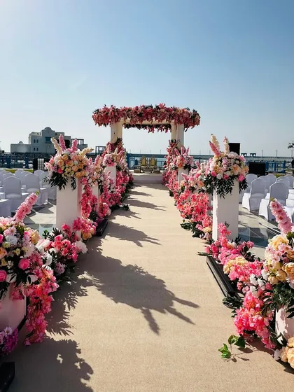 We design dream weddings against the world’s most beautiful backdrops. This romantic seaside wedding aisle, adorned with lush pink and white florals, leads to an elegant mandap under a clear blue sky. 🌊