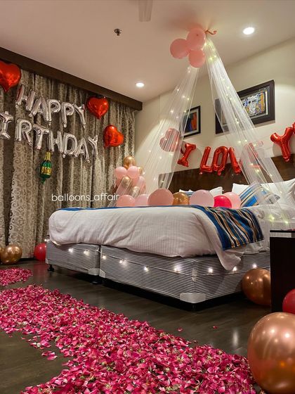 A side view of the rose gold and pink birthday room, highlighting the fairy light canopy and the "I LOVE YOU" foil balloons for a combined birthday and romantic theme.