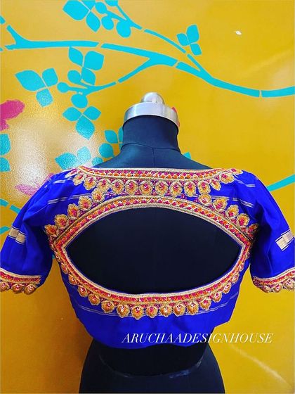 A classic design with a twist. This royal blue blouse has a beautiful eye-shaped back cutout, bordered with detailed red and gold hand embroidery for a striking look.
