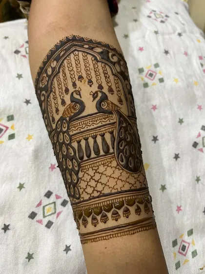 This section of a bridal arm features two peacocks facing each other, a classic symbol of love and beauty in mehendi art.