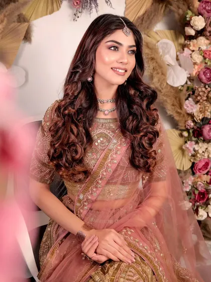 A soft and romantic look featuring a dusty pink and gold lehenga. The delicate jewellery and flowing curls create a perfect look for an engagement photoshoot or ceremony.