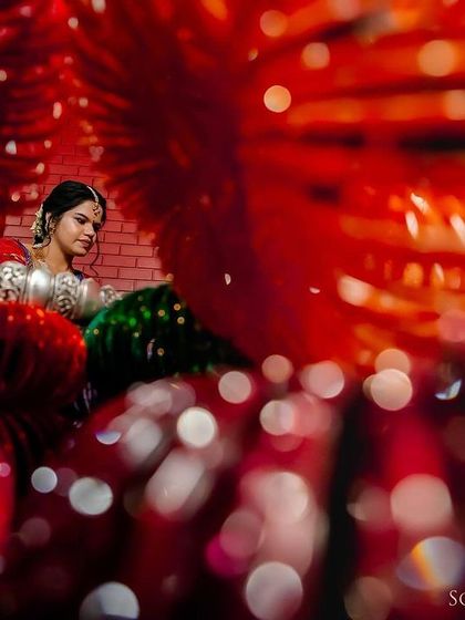 A creative and abstract bridal portrait, shot through a display of red bangles. The effect is colorful, unique, and artistic.