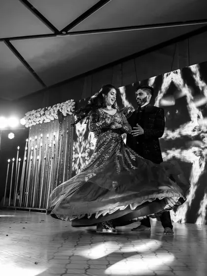 A beautiful black and white shot of the couple's dance performance, the bride's lehenga creating a stunning swirl.