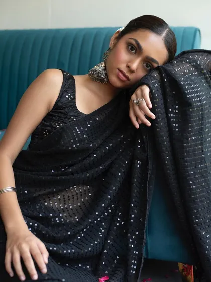 A boho inspired look with a black sequin saree and oxidized silver jewelry. The makeup is minimal and dewy, paired with a sleek low bun for a chic, modern ethnic style.