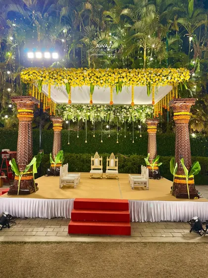 A full view of the traditional marigold mandap, set against a lush green backdrop, perfect for an outdoor Hindu wedding ceremony.