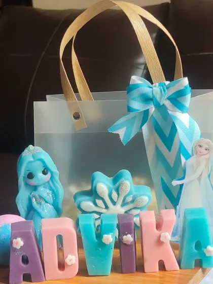 A "Frozen" themed gift bag personalized for Advika. It includes an Elsa doll soap, a snowflake soap, a bath bomb, and her name in soap letters.