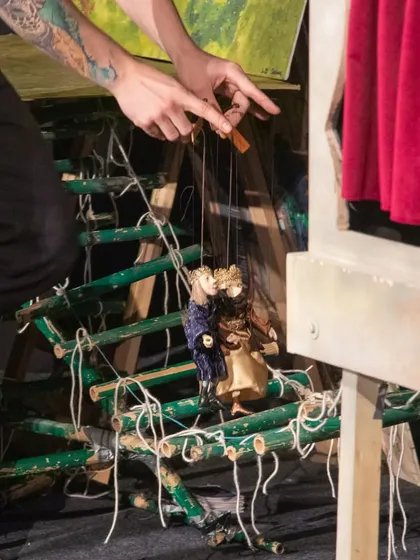 A close-up showing the intricate bamboo structure of the stage and the small royal marionettes from 'Dragon and the Devil'.