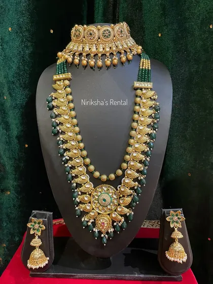 A stunning Kundan-style set with green beads and a large central pendant, perfect for a royal bridal look.