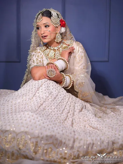 The full view of this white lehenga shows the delicate gold butti work all over the skirt. It’s a look of pure elegance, perfect for a sophisticated bride.