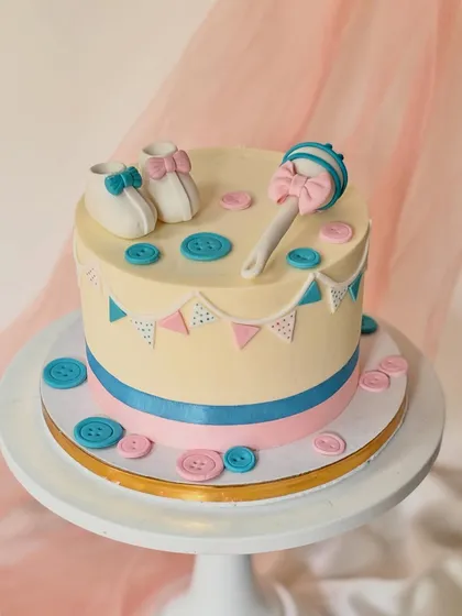 I created this sweet and simple cake for a baby shower. The design features handcrafted fondant baby booties, a rattle, and little buttons in pink and blue, making it perfect for a gender-reveal party or to welcome a new baby.