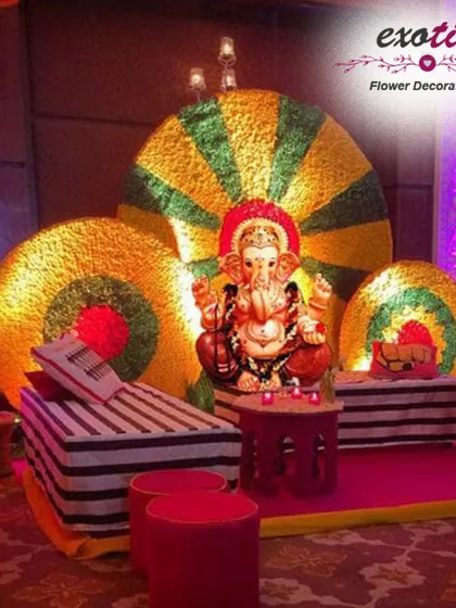 A vibrant and artistic Ganpati setup featuring large, colorful circular backdrops made of flowers, inspired by traditional rangoli patterns. The bold colors and graphic shapes make this a fun and contemporary choice for your festival.