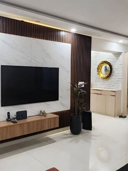 A wider shot of the living and dining area, showing how the modern TV panel complements the classic wall molding and elegant dining set. It's a beautiful blend of contemporary and timeless design.