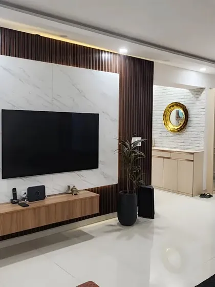 A wider shot of the living and dining area, showing how the modern TV panel complements the classic wall molding and elegant dining set. It's a beautiful blend of contemporary and timeless design.