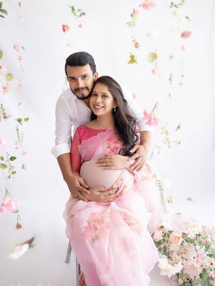 A beautiful family portrait in the making. The couple looks so happy and in love, framed by delicate flowers that add a touch of whimsy to their floral organza saree shoot.