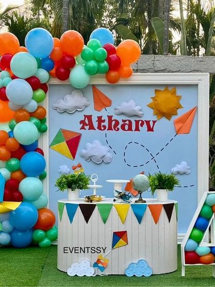 An adventurous "Fly High" theme for a 4th birthday, featuring a rocket ship, hot air balloon, kites, and pinwheels. The colorful balloon garland and sky-blue backdrop create a cheerful and uplifting atmosphere.
