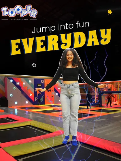 Jump into fun every day. A guest floats in mid-air, surrounded by the cool, electric energy of our glow-in-the-dark park.
