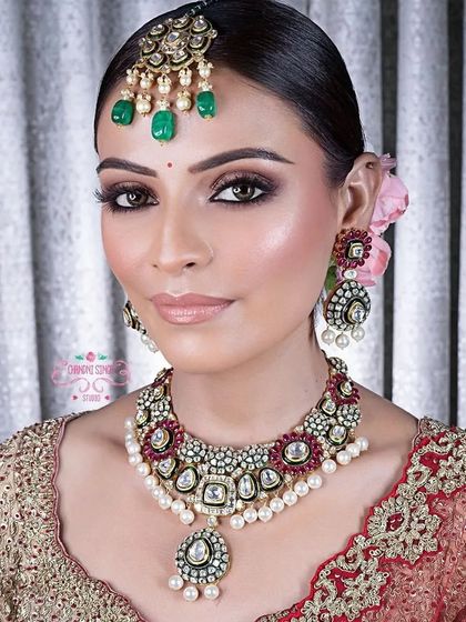 A timeless bridal look featuring classic smokey eyes and a neutral lip color. The makeup is designed to complement the intricate jewelry and outfit, creating a harmonious and regal appearance.
