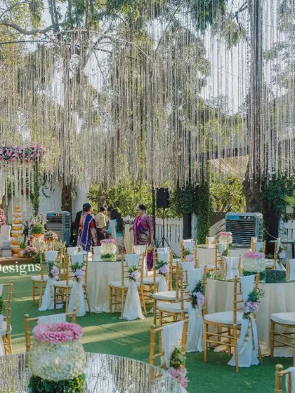 A wide view of an outdoor ceremony setup, showing the guest seating arrangement in relation to the mandap. The hanging crystal strings unify the entire space with a touch of sparkle.