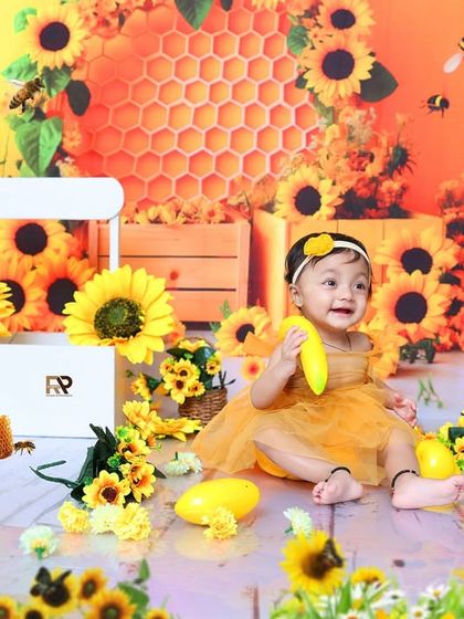 Another shot from the sunflower theme, with the baby girl sitting on a small white chair. The abundance of sunflowers and buzzing bees makes this a lively and happy portrait.