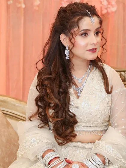 This engagement bride opted for a classic look with an ivory lehenga, soft curls, and timeless makeup.