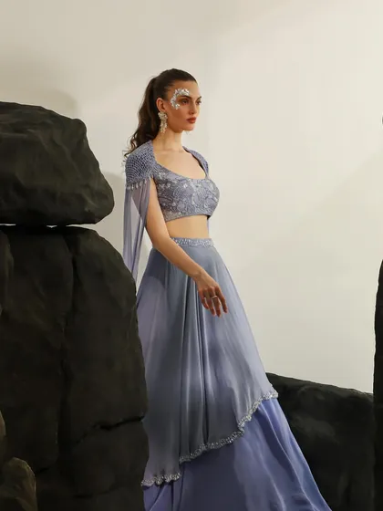 A wide shot of the lavender lehenga, showing how the set pieces create a sense of scale and drama. The pose is elegant and powerful.