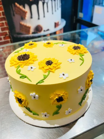 A cheerful yellow cake decorated with bright and sunny sunflowers made from buttercream.