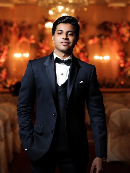 A classic portrait of the groom in his tuxedo. The warm, ambient lighting of the reception hall creates a sophisticated and timeless look.