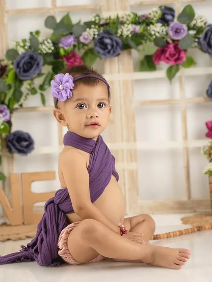 A simple and sweet first birthday portrait. The lavender wrap and floral backdrop create a soft, dreamy atmosphere.