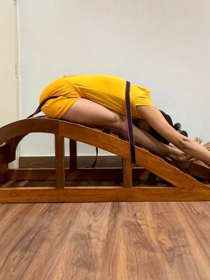 Using a backbend bench and belt for Janu Sirsasana (Head-to-Knee Pose) allows for a deep, supported forward bend. The belt helps to extend the spine, while the bench supports the torso, preventing strain.