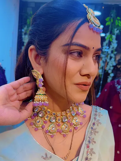 A close-up of the lilac-beaded Kundan jewellery set against the sea-green lehenga, showing the beautiful color combination.
