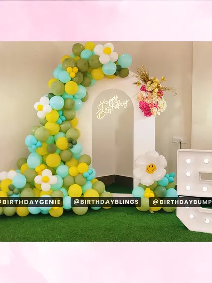 A simple and sweet balloon arch in shades of green and yellow, with daisy accents. Set on artificial turf with a light-up number '5', this is a fresh and fun setup.