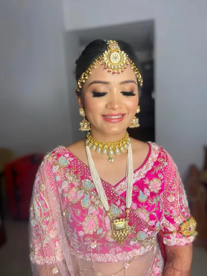 Embracing tradition with this beautiful pink bridal look for Pooja. The makeup is classic and elegant, with a focus on radiant skin and defined eyes.
