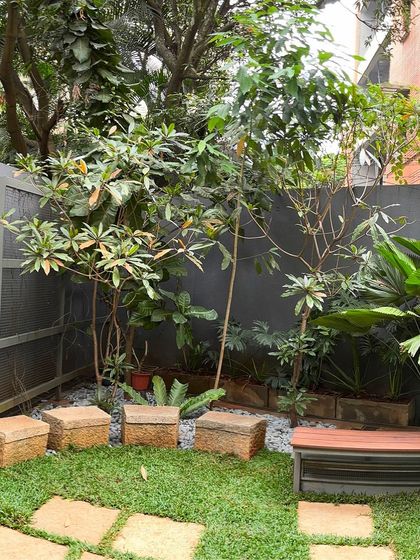 We designed this quiet seating nook with natural stone stools and a wooden bench, surrounded by a variety of foliage. It’s a perfect example of how we create functional, peaceful spots within a larger garden.