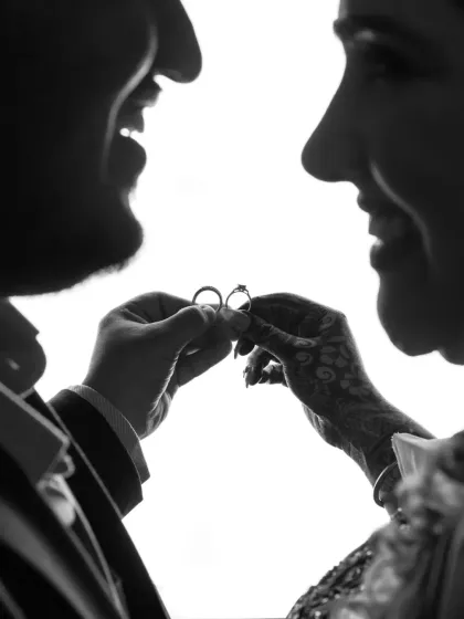 An artistic black and white silhouette of the couple holding their engagement rings, focusing on the symbolism of their union.