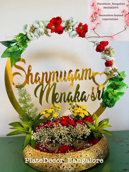 This is a personalized ring platter I designed for an engagement. It features the couple's names in a beautiful golden script, surrounded by fresh flowers, making the moment even more special.