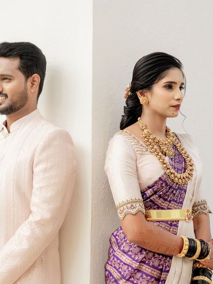 A stylish shot of a couple. Her purple and white saree with a simple embroidered blouse is modern and chic, while his light pink sherwani adds a touch of softness.