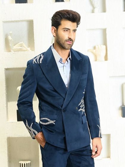 A full view of the double-breasted blue velvet suit. The placement of the silver embroidery adds a dynamic and artistic flair to the classic silhouette.