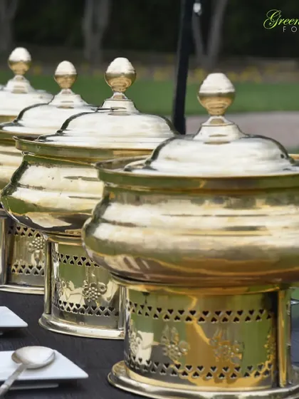 For outdoor events, presentation is key. We use these beautiful brass chafing dishes that not only keep the food warm but also add a touch of traditional elegance to the buffet setup, perfect for a classic wedding theme.