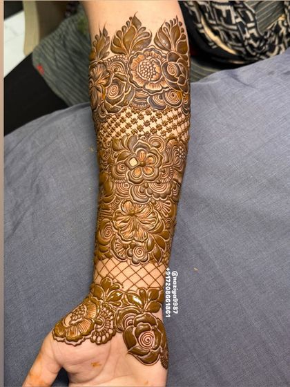This arm design combines floral patterns with classic net or 'jaali' work. The criss-cross pattern adds a beautiful texture to the overall mehandi.