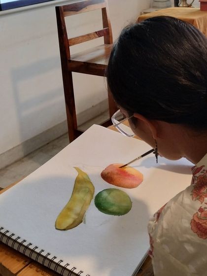 A student practices painting different fruits and vegetables. This still life exercise is fundamental to understanding form, light, and shadow in watercolor.