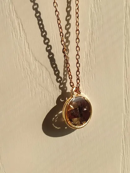 This is another look at the rose gold pendant with preserved rose petals. The simple chain and classic round shape make it a versatile accessory that can be worn with any outfit.