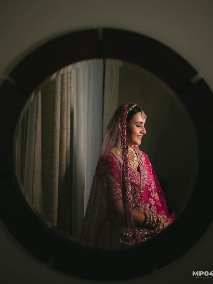 A creative shot of the bride's reflection in a mirror, capturing a quiet moment of her getting ready.