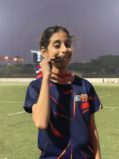 That "I did it" smile. Nataniya proudly bites her bronze medal, a reward for her speed and determination on the track.