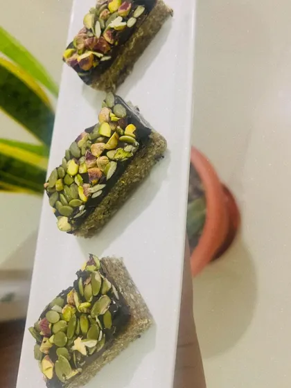 These are my Pumpkin Seed & Fig nutritional bars, topped with rich vegan chocolate and a generous sprinkle of pistachios. They are the ideal on-the-go snack, providing sustained energy without any refined sugar.