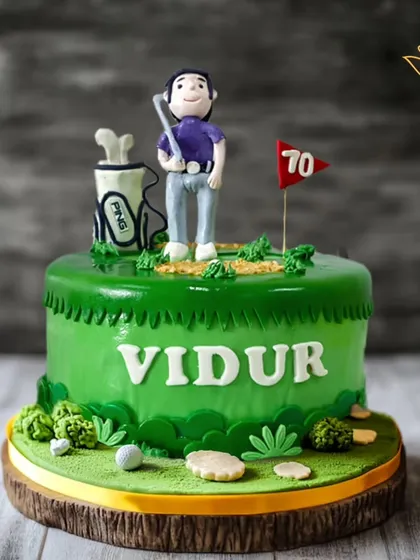 A hole-in-one of a cake for a golf lover's 70th birthday. This design features a green golf course, a fondant golfer, and a flag marking the special milestone.