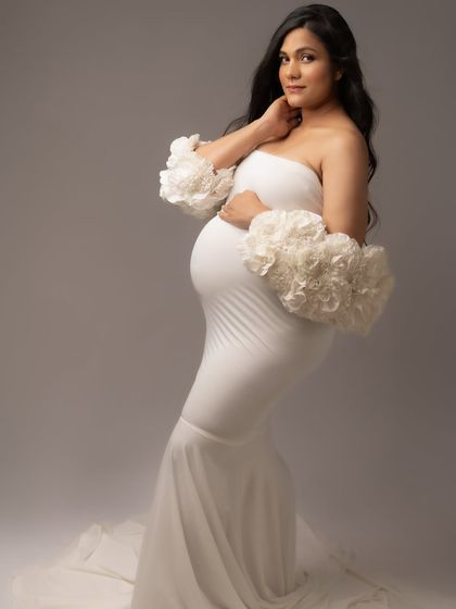 This white gown with floral sleeve details is the definition of grace. A perfect choice for a soft and elegant maternity portrait.