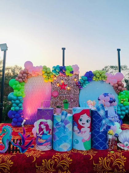 A closer look at the outdoor mermaid party decor, showing the character pedestals and balloon colors.