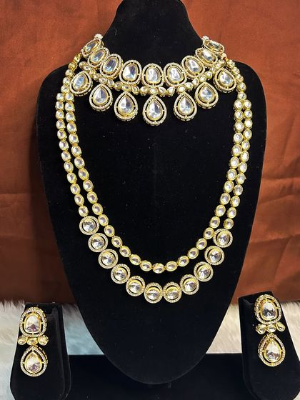 This elegant Kundan set features large, clear stones for a classic and sophisticated bridal look. The rental set includes a choker with teardrop-shaped stones and a matching double-layered long necklace, paired with beautiful earrings.