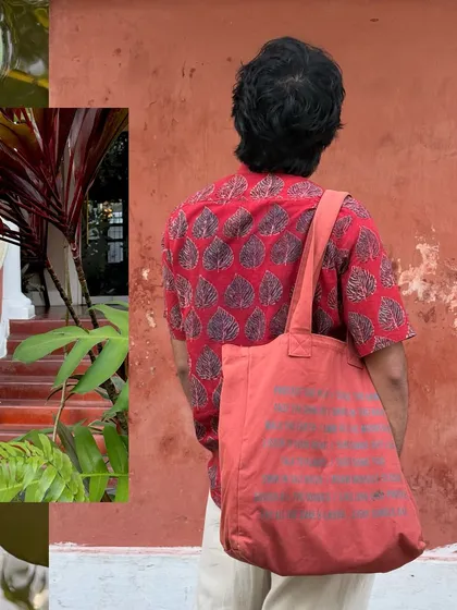 A shot of my back against a red wall, carrying a tote bag, perfectly capturing the traveler's aesthetic.