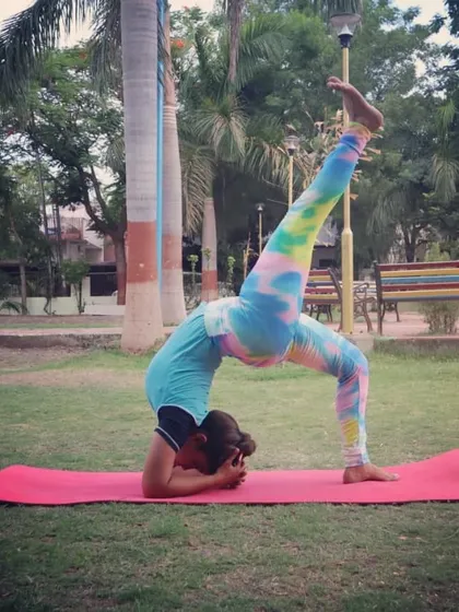 A one-legged Scorpion Pose in a headstand, practiced outdoors. This advanced variation deeply opens the spine and shoulders while challenging balance and core stability.